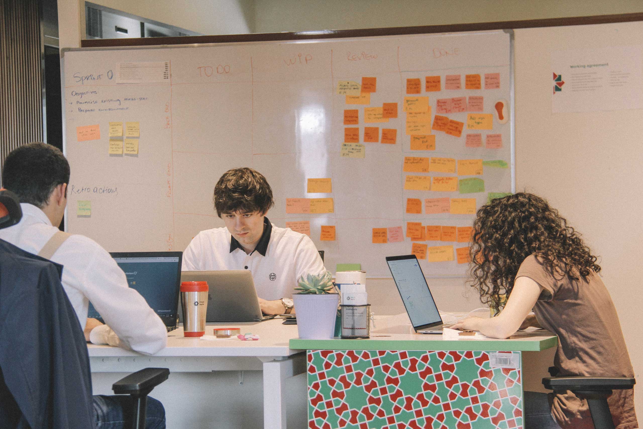 three people in an office working on laptops