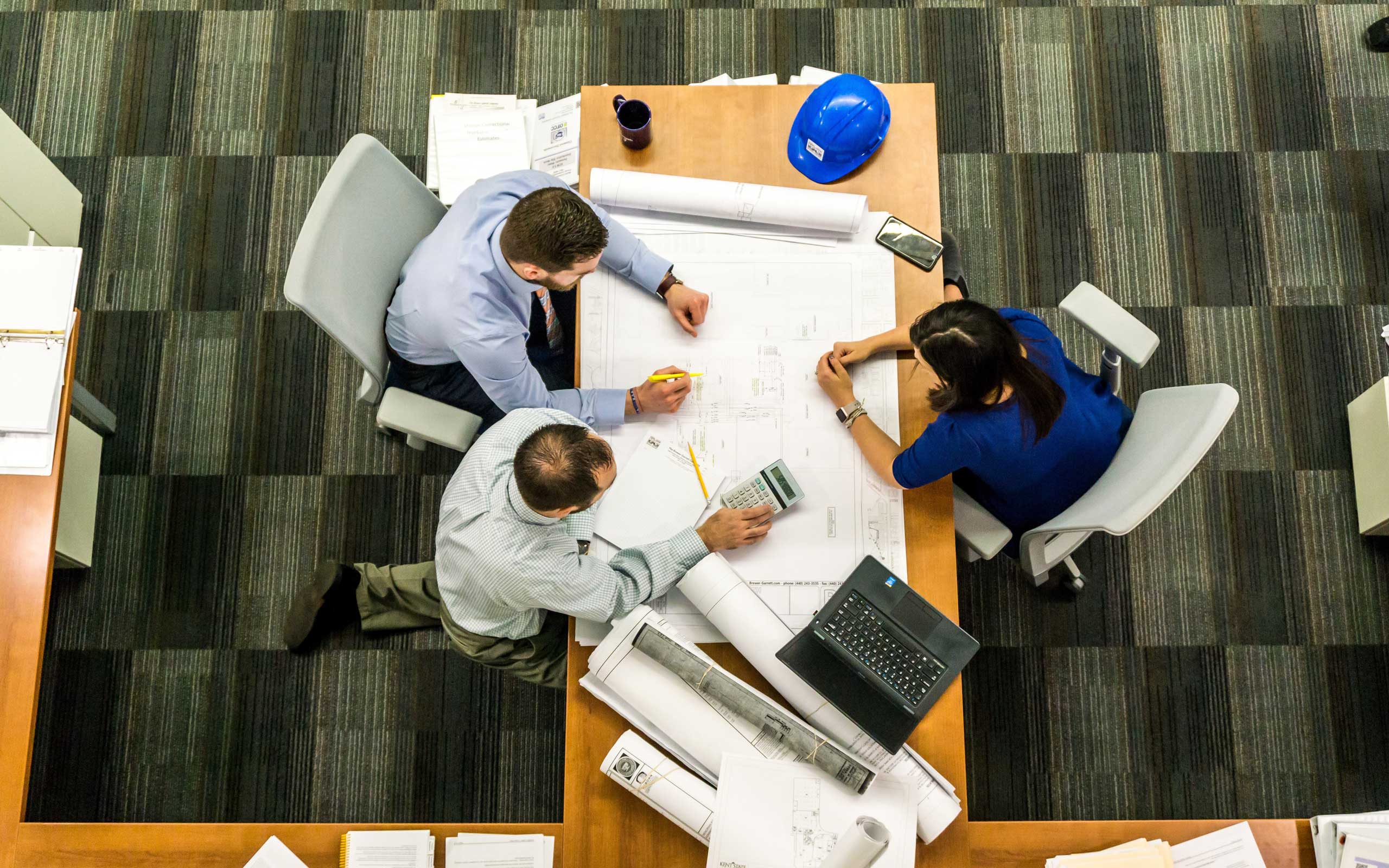 three people gathered around a table discussing plans